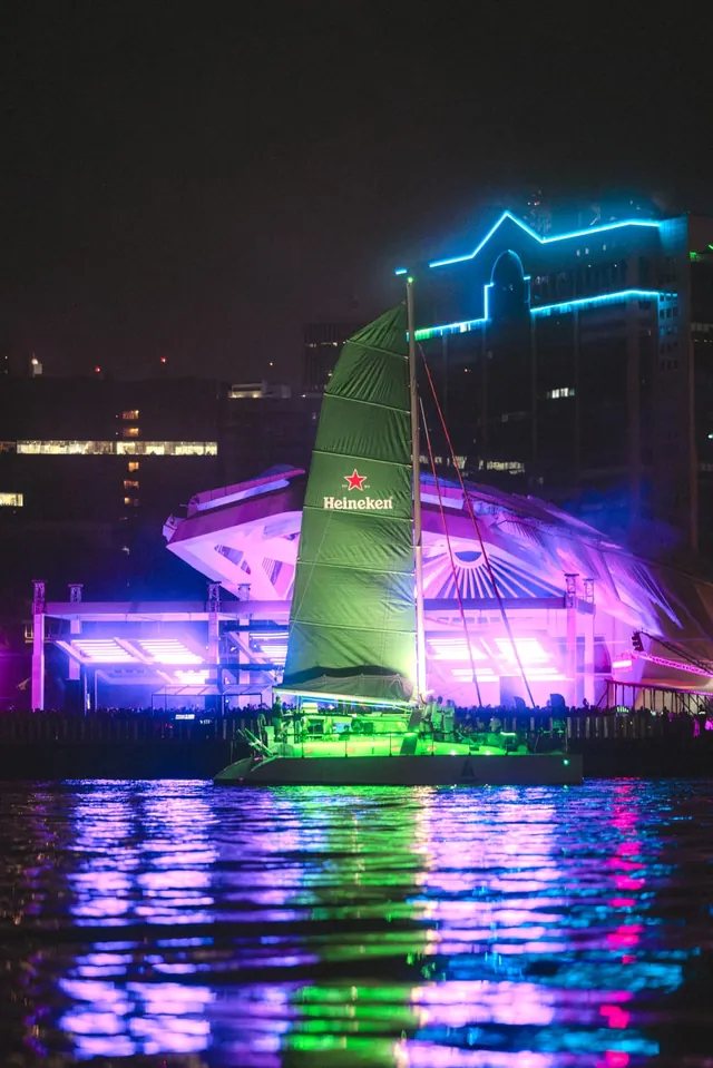 Veleiro com identidade visual Heineken na vela, fotografado à noite.