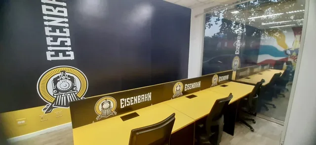 Ambientação corporativa da Eisenbahn aplicada a parede, vidro e mobiliário.