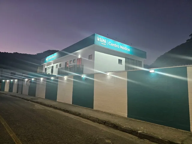 Fachada iluminada do centro médico Klini à noite.